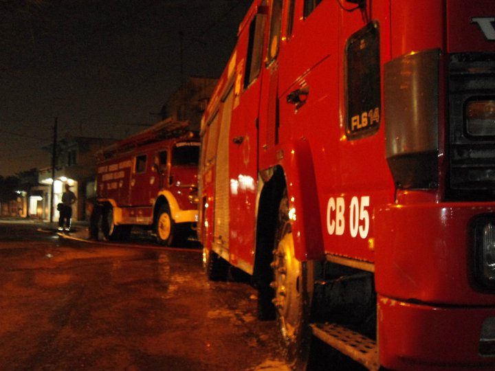 Autobombas de bomberos voluntarios en una calle mojada de noche